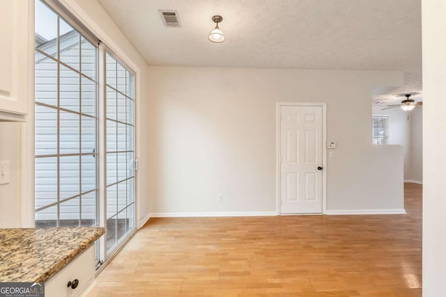 interior space with ceiling fan, a healthy amount of sunlight, a textured ceiling, and light wood-type flooring