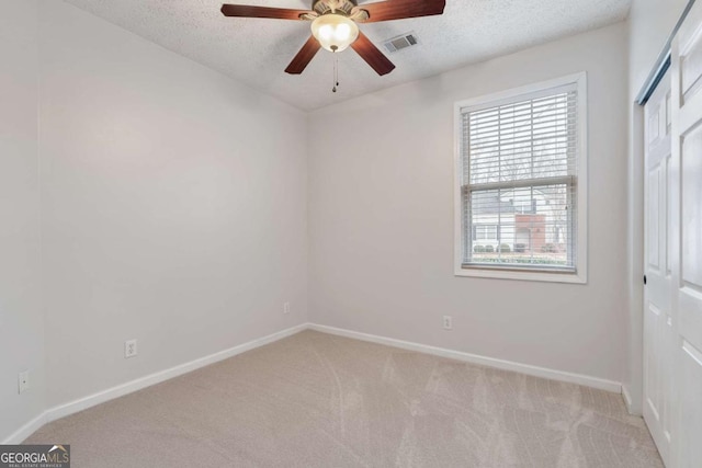 unfurnished room with ceiling fan, light colored carpet, and a textured ceiling