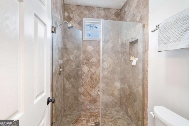 bathroom featuring a shower with door, a textured ceiling, and toilet