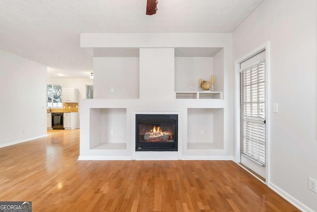 unfurnished living room with a textured ceiling and light wood-type flooring