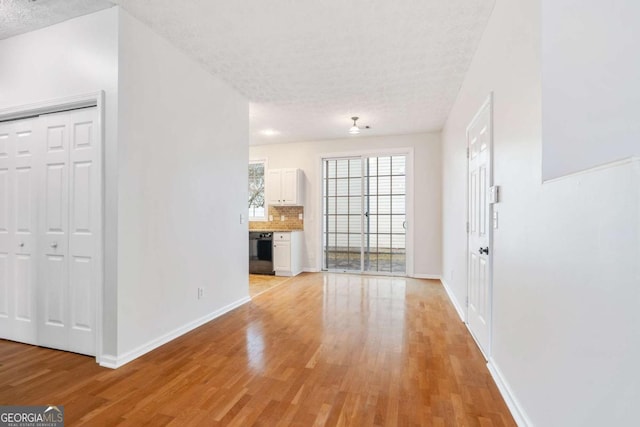 unfurnished living room with a textured ceiling and light wood-type flooring