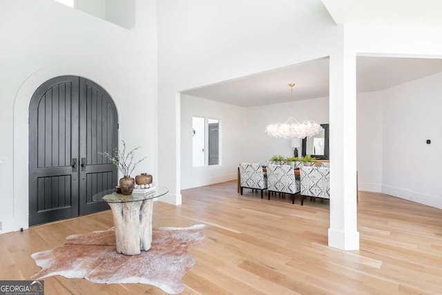 foyer entrance featuring an inviting chandelier, hardwood / wood-style flooring, and a high ceiling