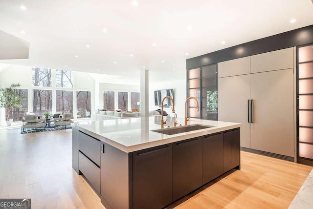 kitchen featuring a kitchen island with sink, sink, and light hardwood / wood-style floors