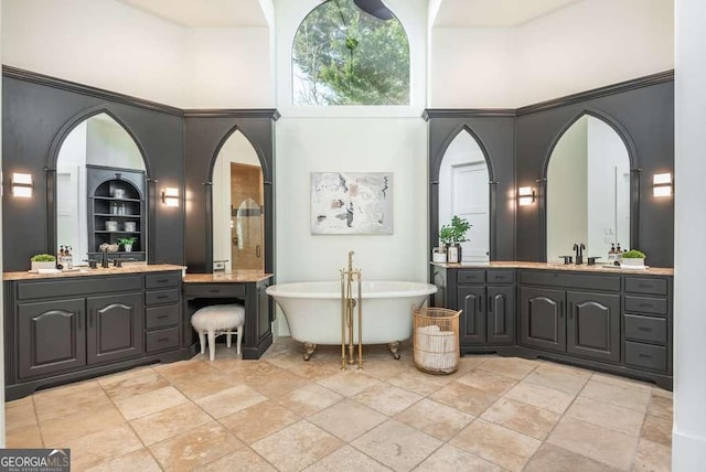 bathroom featuring a towering ceiling, vanity, built in features, and a washtub