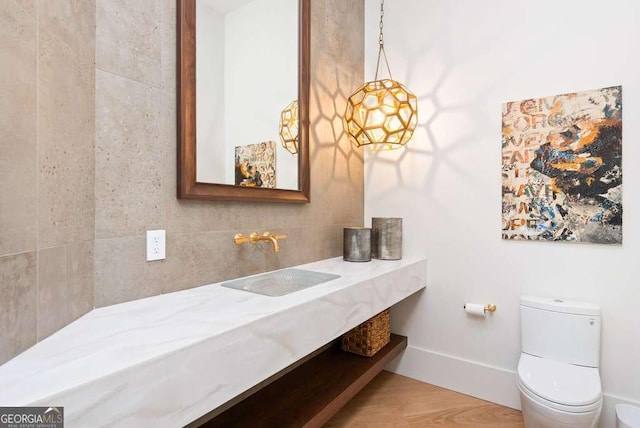 bathroom featuring sink, backsplash, hardwood / wood-style floors, and toilet