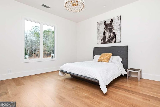 bedroom with an inviting chandelier and wood-type flooring