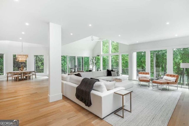 living room featuring high vaulted ceiling, ceiling fan with notable chandelier, plenty of natural light, and light hardwood / wood-style floors