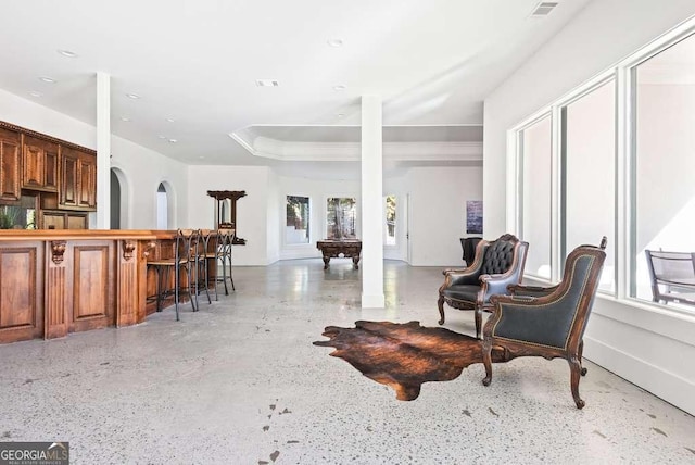 interior space with a tray ceiling and indoor bar