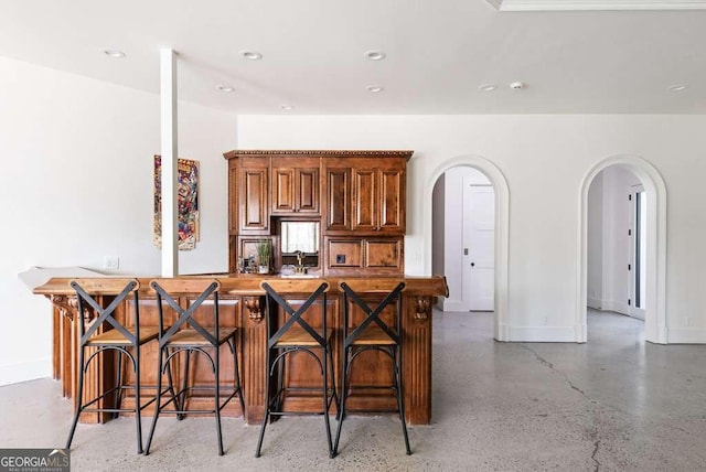 kitchen with a breakfast bar area and concrete floors