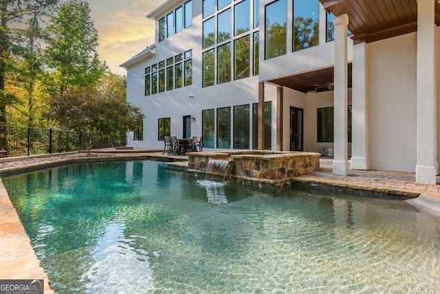 pool at dusk with an in ground hot tub, ceiling fan, and a patio area