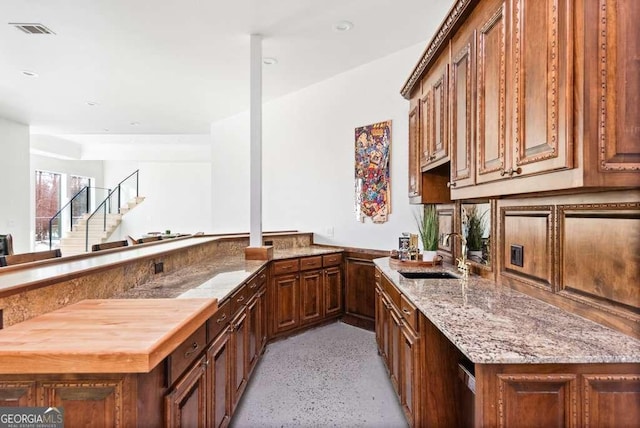 kitchen featuring light stone counters, kitchen peninsula, and sink