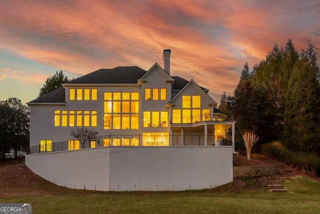 back house at dusk with a balcony