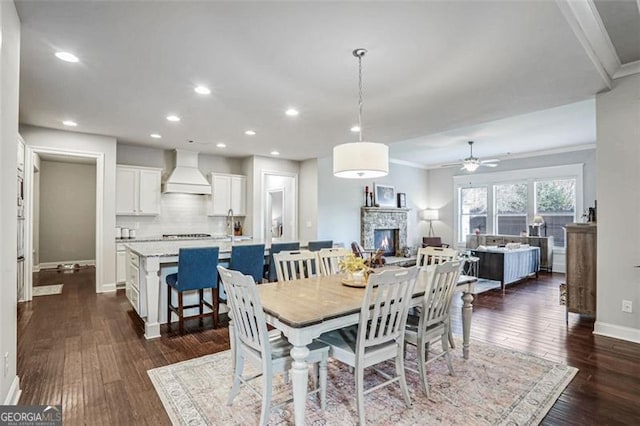 dining space featuring crown molding, dark hardwood / wood-style floors, ceiling fan, and a fireplace