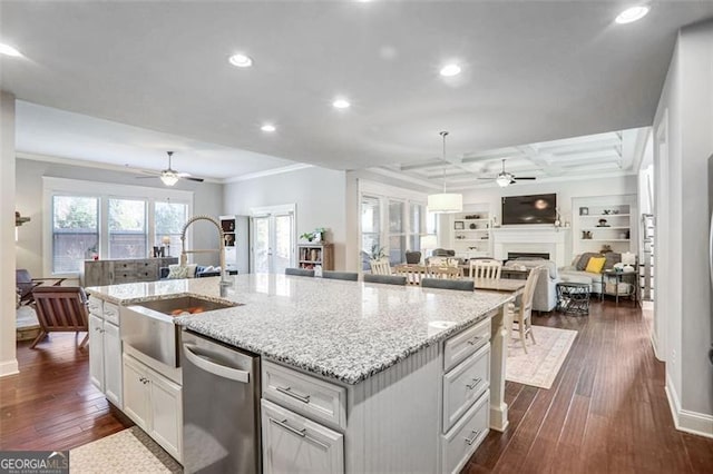 kitchen with decorative light fixtures, sink, a kitchen island with sink, stainless steel dishwasher, and dark wood-type flooring