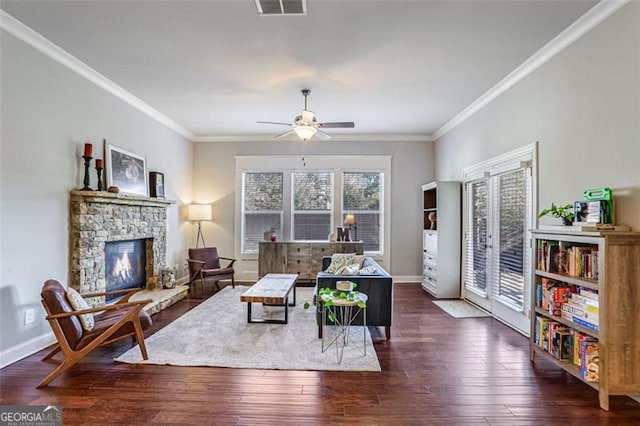 living room featuring ornamental molding, dark wood-type flooring, ceiling fan, and a fireplace