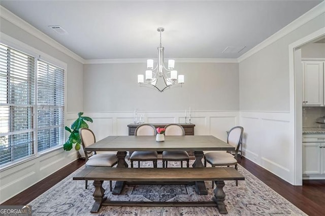 dining area featuring crown molding, dark wood-type flooring, and a chandelier