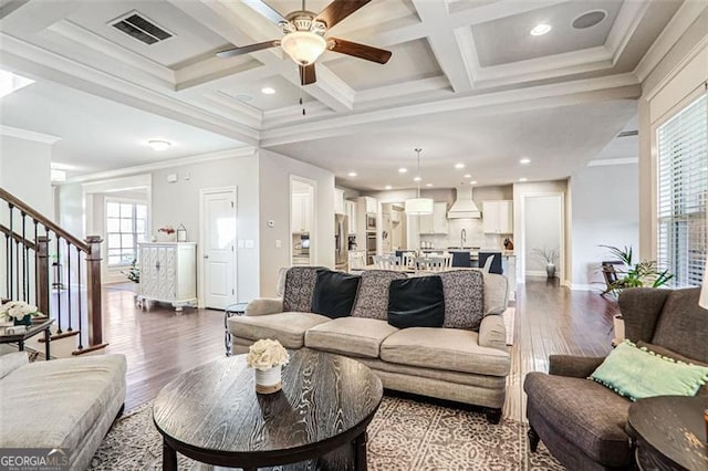 living room with ornamental molding, coffered ceiling, and a wealth of natural light