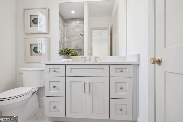 bathroom with tiled shower, vanity, and toilet