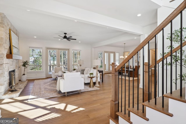 living room featuring plenty of natural light, a stone fireplace, light hardwood / wood-style floors, and french doors