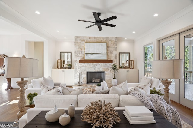 living room featuring ceiling fan, ornamental molding, a fireplace, and wood-type flooring