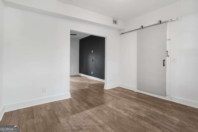 spare room featuring wood-type flooring and a barn door