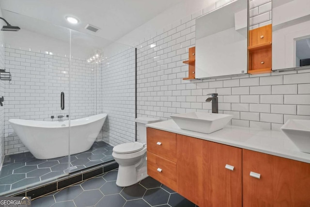 bathroom featuring tile patterned flooring, tile walls, vanity, a tub, and toilet