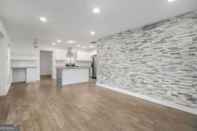 unfurnished living room with sink, hardwood / wood-style flooring, and a skylight