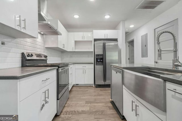 kitchen with tasteful backsplash, white cabinetry, sink, stainless steel appliances, and wall chimney range hood