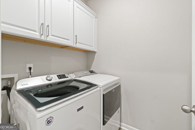 clothes washing area featuring cabinets and washing machine and clothes dryer