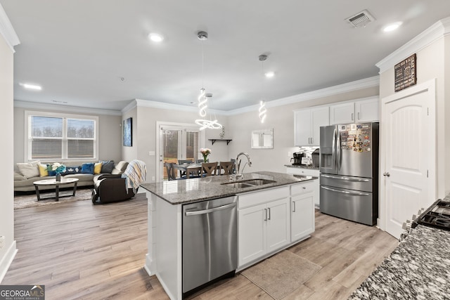 kitchen with sink, hanging light fixtures, appliances with stainless steel finishes, an island with sink, and white cabinets