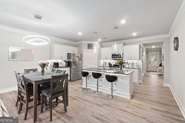 kitchen featuring pendant lighting, appliances with stainless steel finishes, a center island with sink, and white cabinets