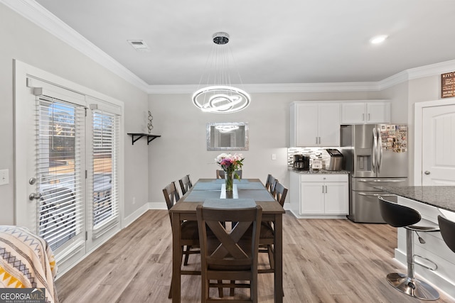 dining area with ornamental molding and light hardwood / wood-style floors