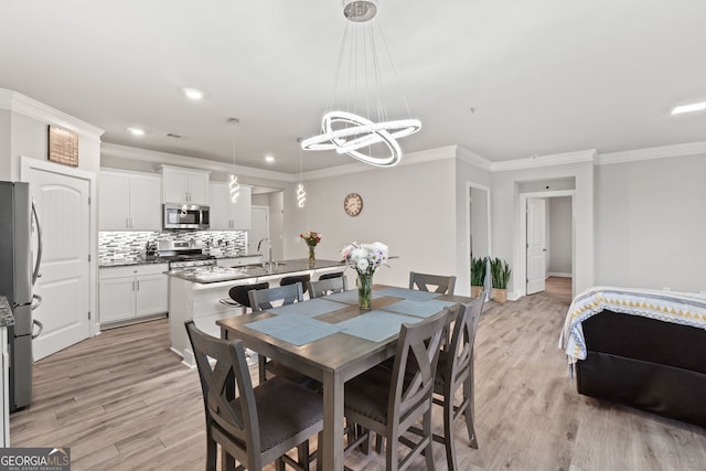 dining area with crown molding, sink, and light hardwood / wood-style flooring