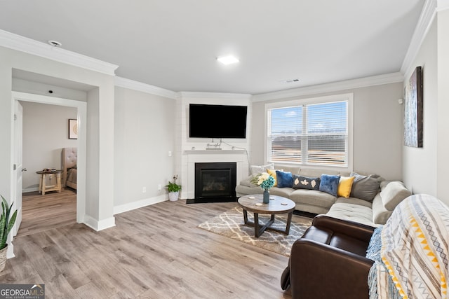 living room with crown molding, a large fireplace, and light wood-type flooring