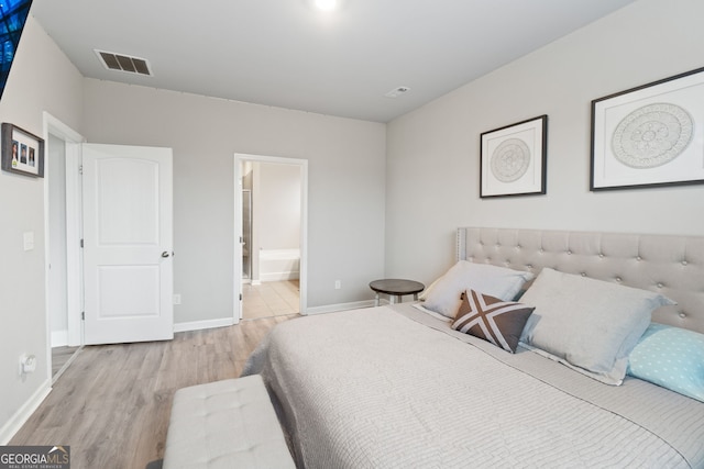 bedroom featuring ensuite bath and light hardwood / wood-style floors