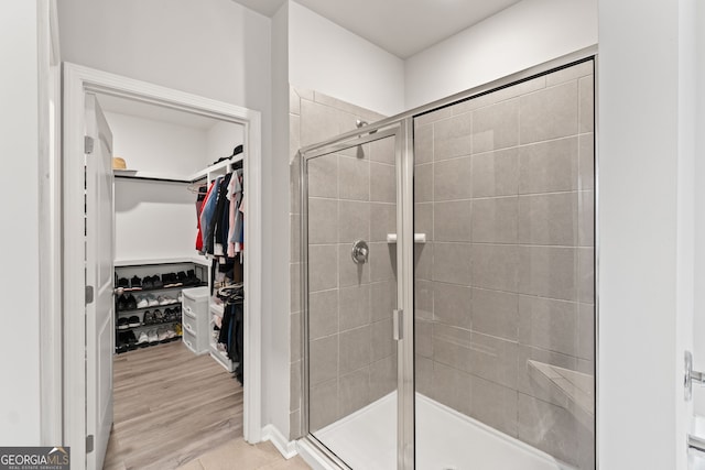 bathroom with a shower with door and hardwood / wood-style floors