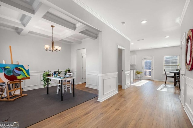 dining area featuring coffered ceiling, an inviting chandelier, ornamental molding, beam ceiling, and light hardwood / wood-style floors