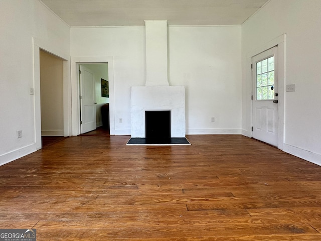 unfurnished living room featuring ornamental molding and dark wood-type flooring