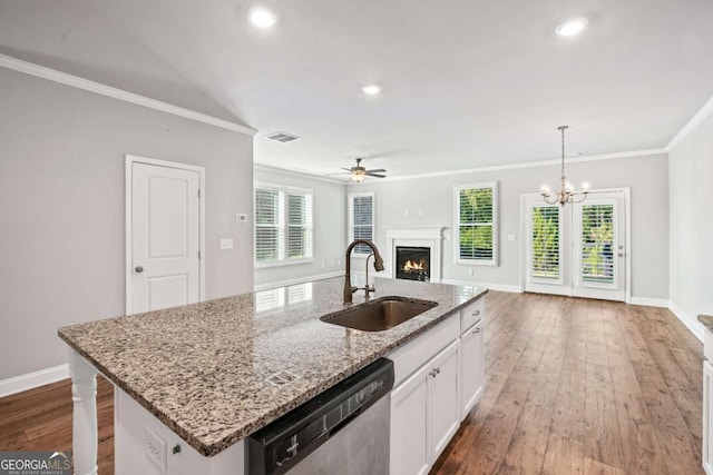 kitchen with decorative light fixtures, dishwasher, sink, white cabinets, and a center island with sink