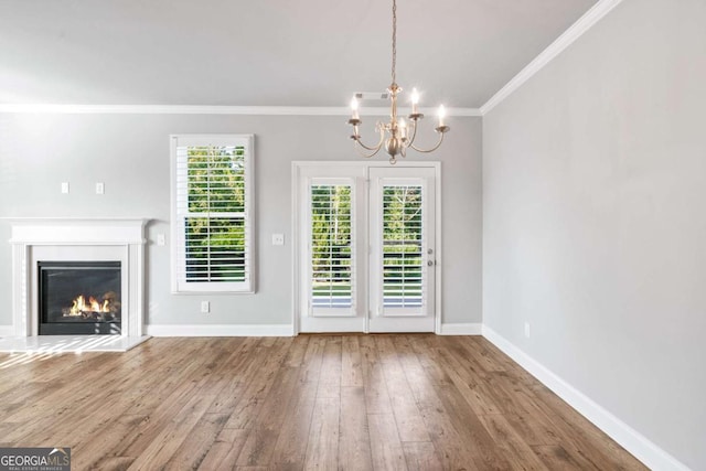 unfurnished living room with crown molding, hardwood / wood-style floors, and a notable chandelier