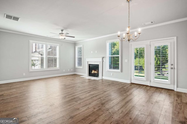 unfurnished living room with wood-type flooring, ornamental molding, ceiling fan with notable chandelier, and a healthy amount of sunlight