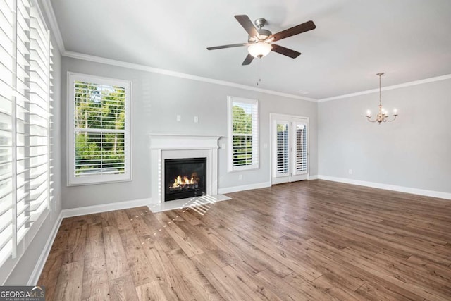 unfurnished living room with hardwood / wood-style flooring, ornamental molding, plenty of natural light, and ceiling fan with notable chandelier