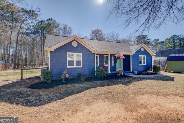 single story home with a front lawn, a storage unit, and a porch