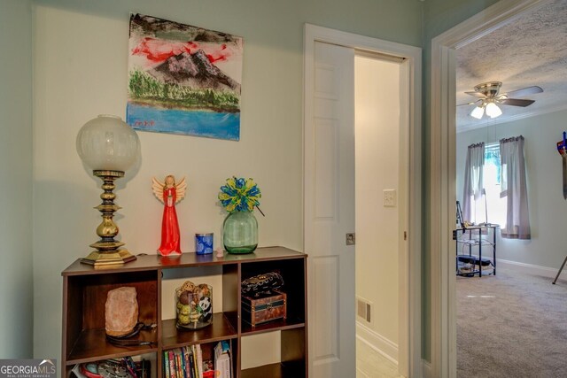 hallway with carpet, visible vents, crown molding, and baseboards