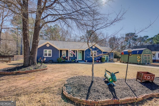 ranch-style house with a shed, an outdoor structure, fence, and a front yard