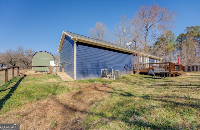 view of side of property with a wooden deck, fence, and a yard