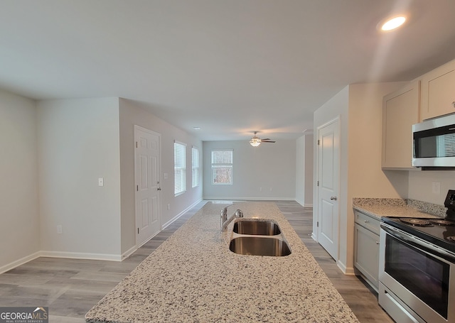 kitchen featuring sink, ceiling fan, stainless steel appliances, light stone counters, and white cabinets