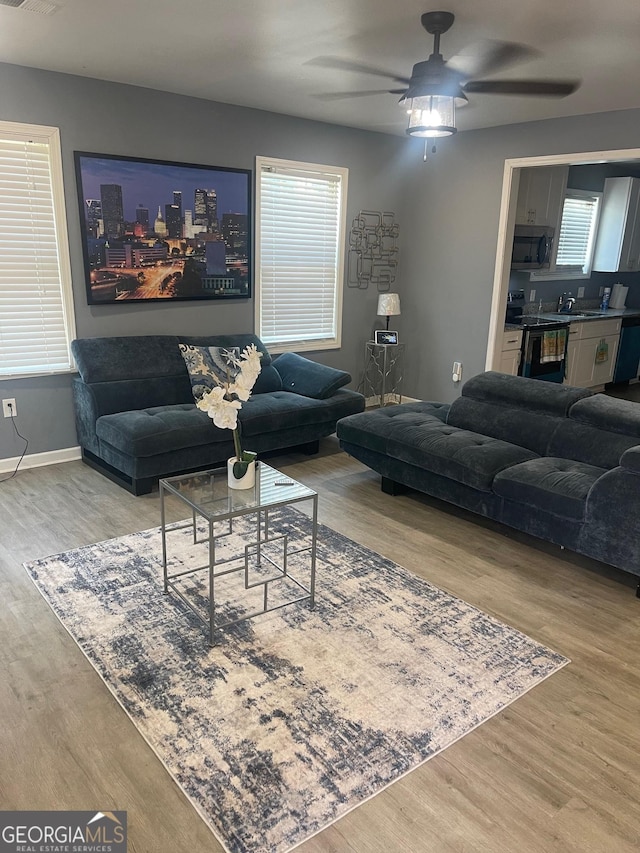 living room featuring wood-type flooring, sink, and ceiling fan