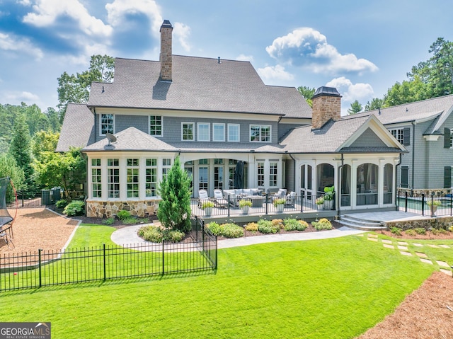 back of house featuring a lawn, a chimney, a patio area, and a sunroom