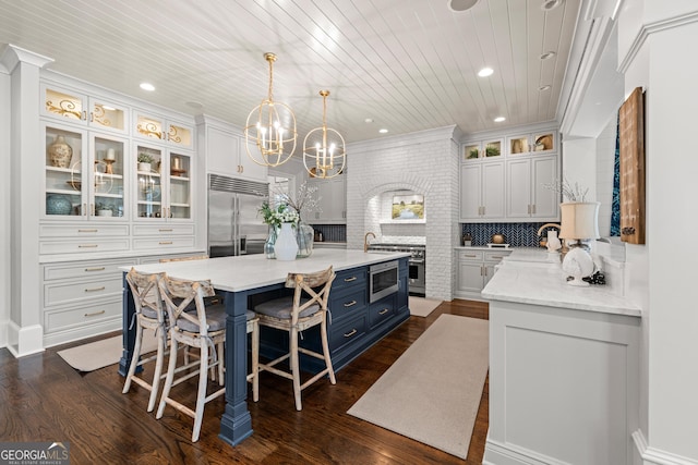 kitchen with wooden ceiling, a breakfast bar, a center island, built in appliances, and blue cabinetry